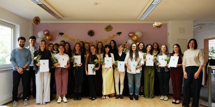 Absolventinnen und Absolventen der Ergotherapie Schule Mainz zeigen Ihre Examen in die Kamera.